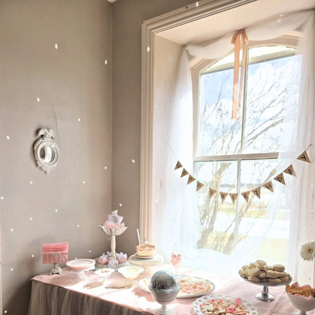 Dessert table decorated with a pink tablecloth for a child's ballerina and bows birthday party.