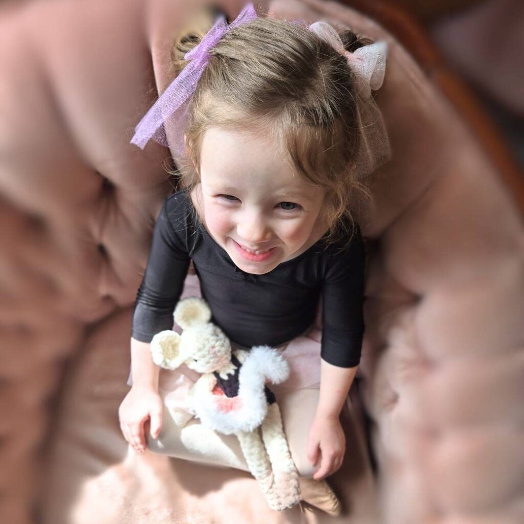 Little girl in a ballet dress holding a ballerina mouse doll.