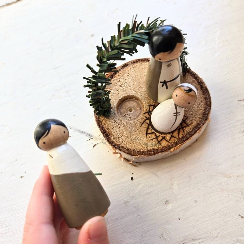 Child's hands playing with a mini peg doll Nativity set.