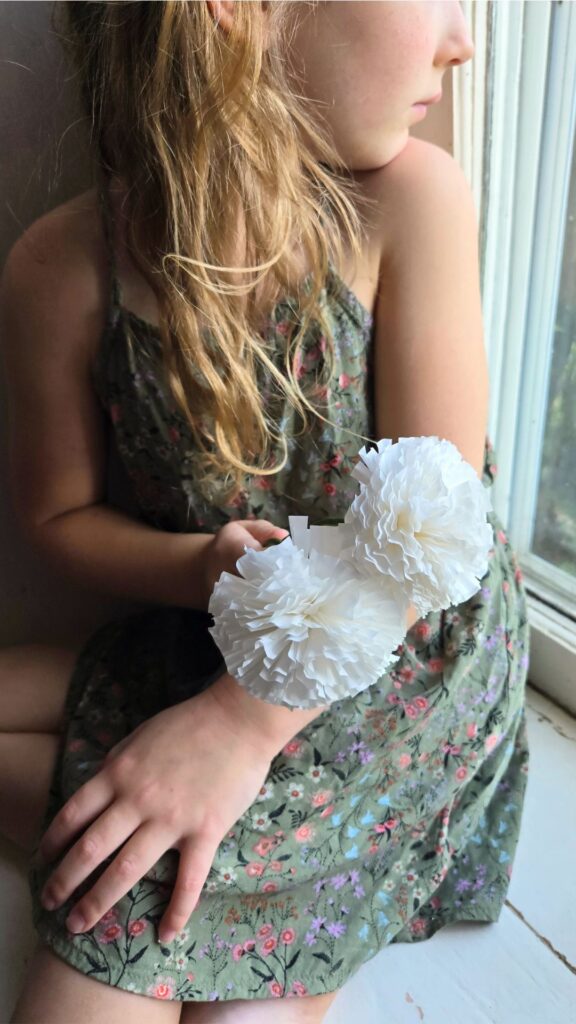 a young girl holding handmade paper flowers