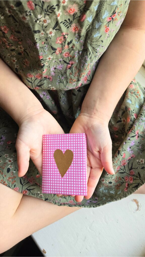 A child's hands holding a handmade booklet